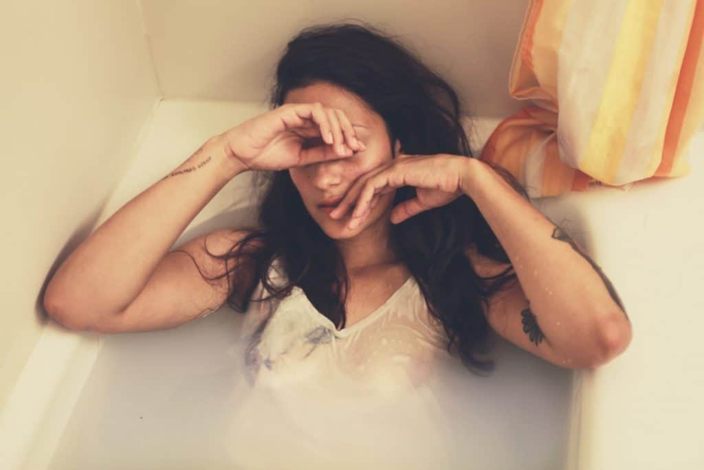 woman in bathtub with clothes on looking upset